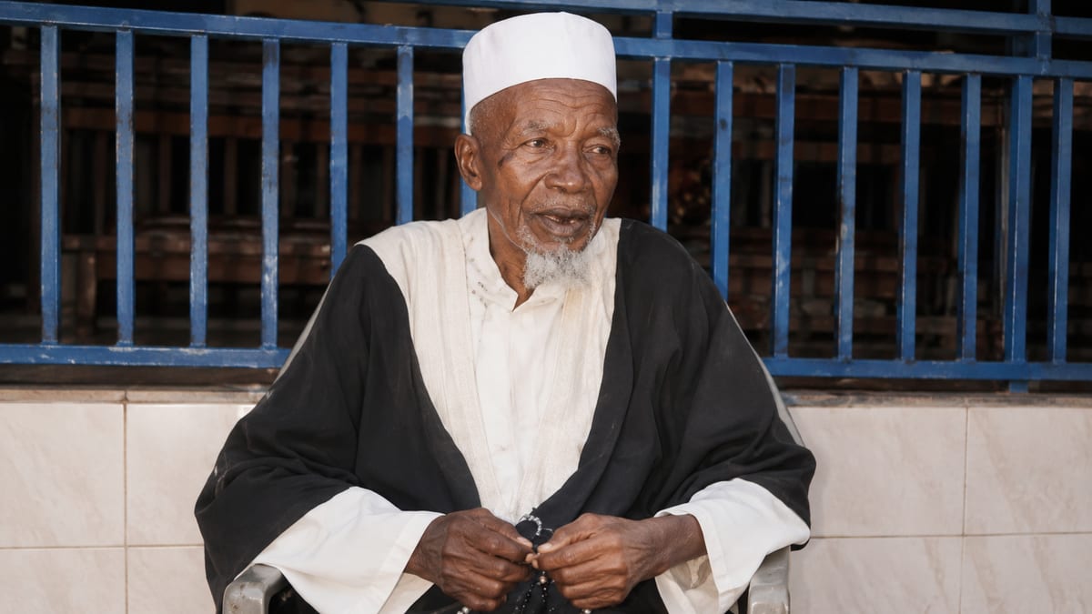 Vieux sage égrenant son chapelet, en boubou noir et blanc